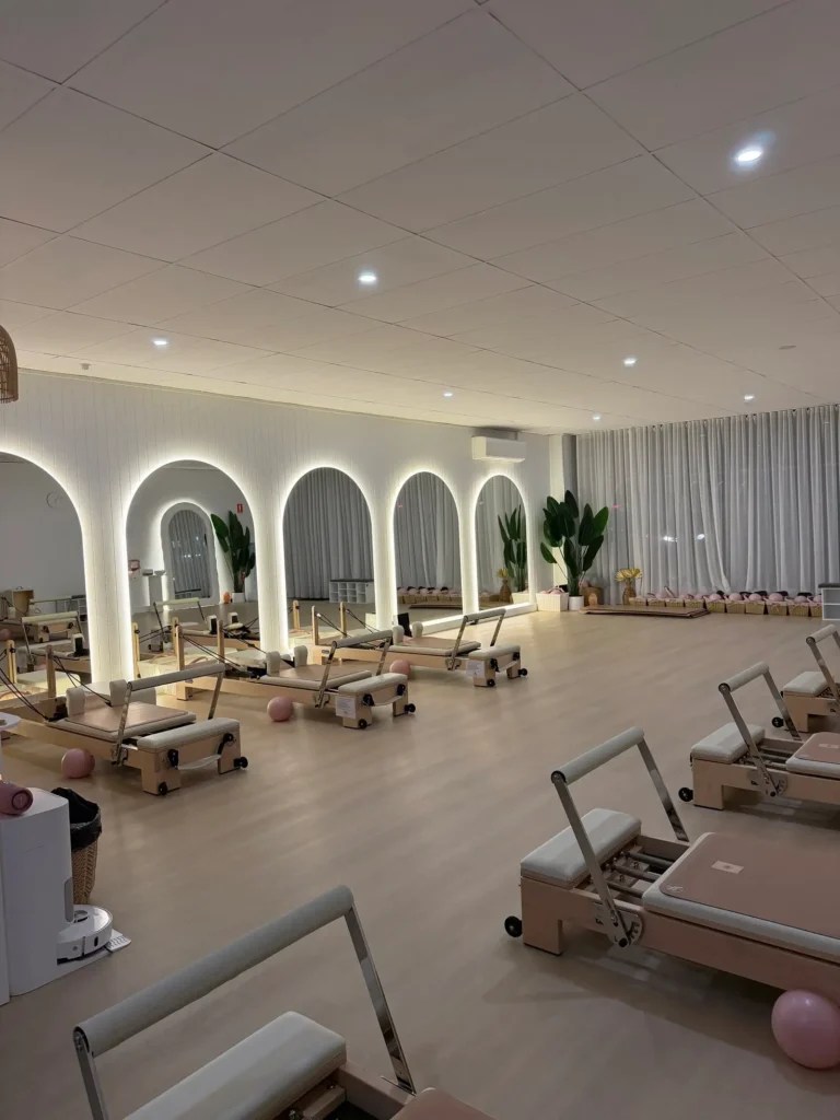 Modern reformer Pilates studio with multiple machines, arched mirrors and soft lighting